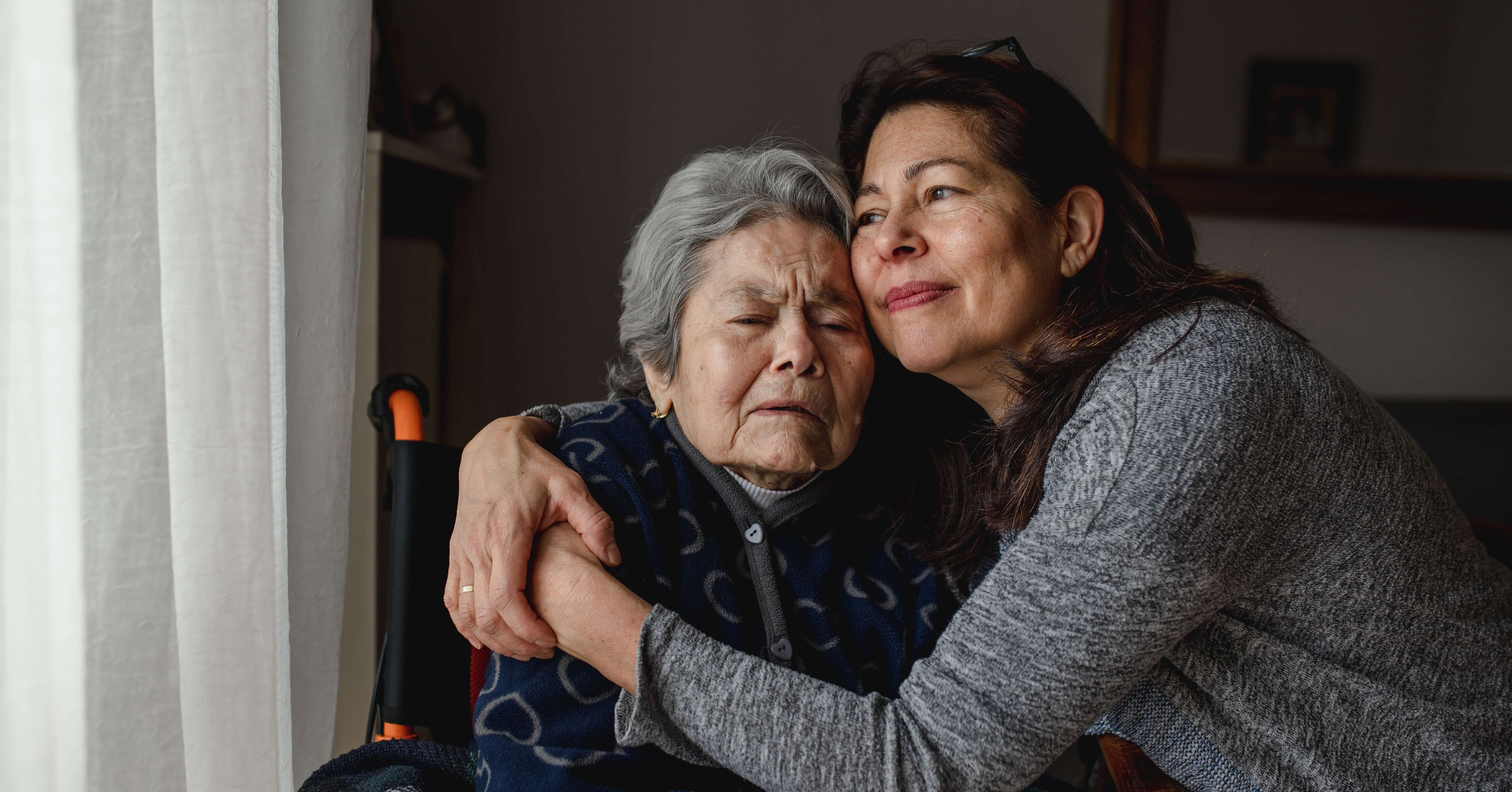 Caregiving woman hugs elderly family member